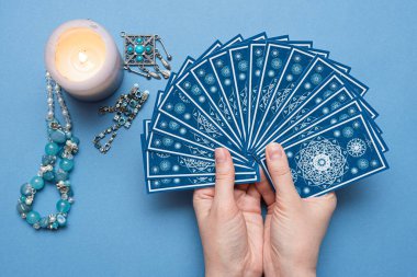 Falcı elinde tarot kartları tutuyor..