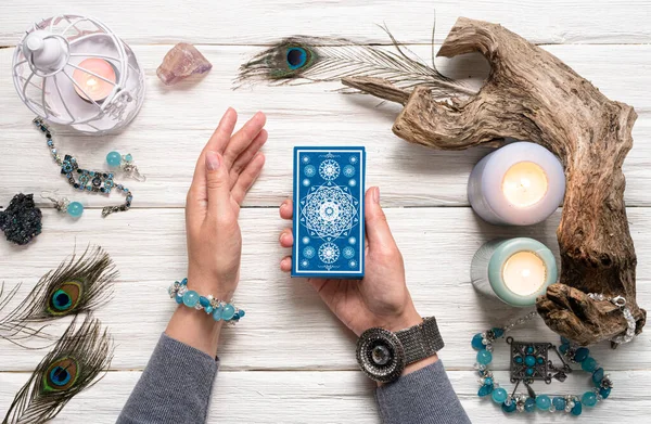 Falcı kadın ve beyaz ahşap masa üzerinde mavi tarot kartları..