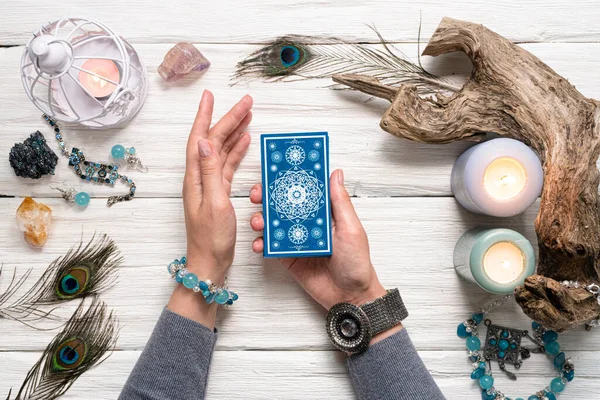 Falcı kadın ve beyaz ahşap masa üzerinde mavi tarot kartları..