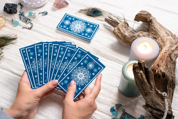 Falcı kadın ve beyaz ahşap masa üzerinde mavi tarot kartları..