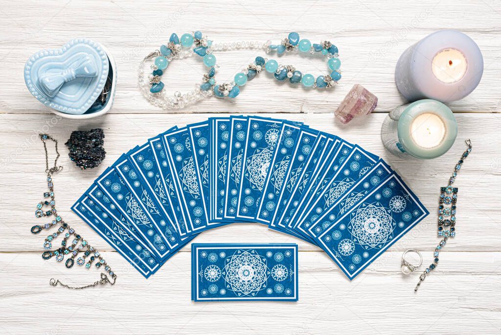 Blue tarot cards on white wooden table background.