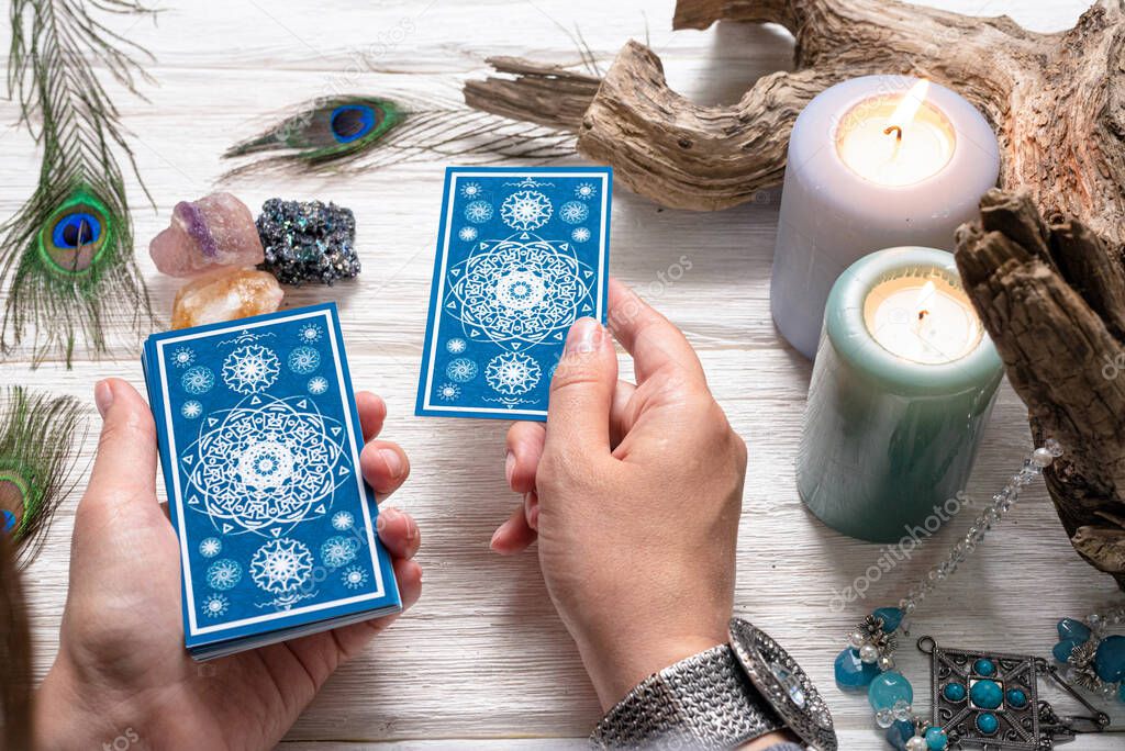 Fortune teller woman and a blue tarot cards over white wooden table background.