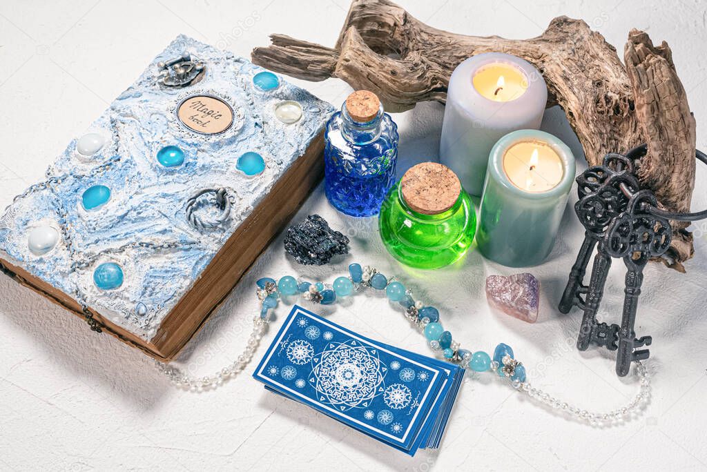 Tarot cards and magic book on white stone table background.
