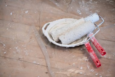 Ahşap zemin zeminindeki tepside kirli boya silindirleri..