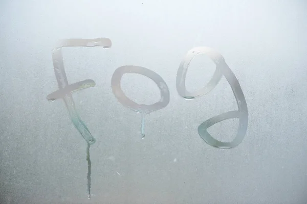 The fog the inscription on the wet window background.