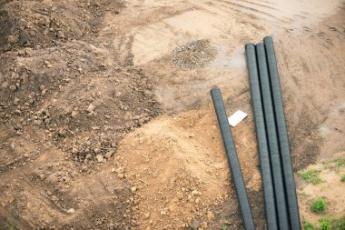 İnşaat arka planında büyük plastik su boruları yığını.