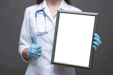 Hekim doktor diploma sertifikası şablonu verdi. Boş bir fotoğraf çerçevesi olan doktor olumlu bir hareket gösteriyor..
