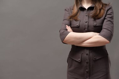 Sert kadın patron ellerini çapraz yapıp arka planda fotokopi çekerek duruyor..