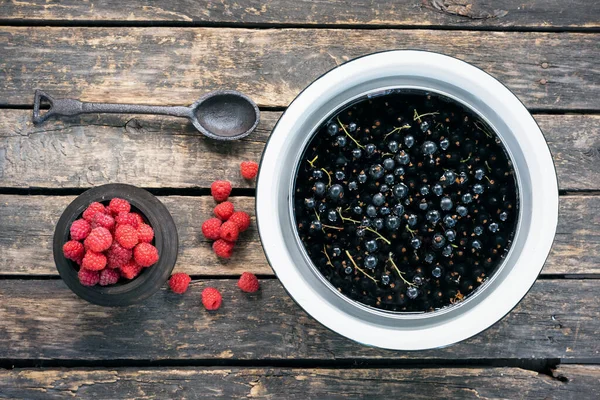 Raspberry and black currant in the container on the garden table background.