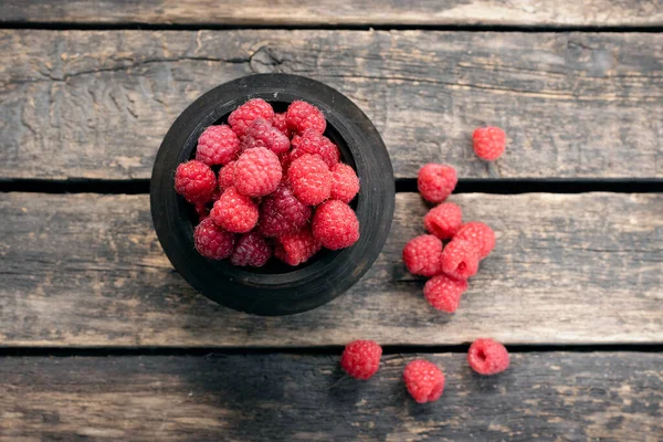 Raspberry fruits in the jar on old rural kitchen table background.