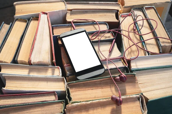 Mobile phone with blank screen with copy space and old books. Electronic book concept.