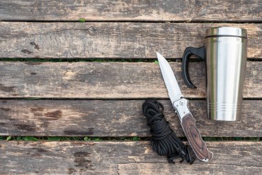 Ahşap arka planda paslanmaz bardak, bıçak ve ip fotokopi alanı ile..