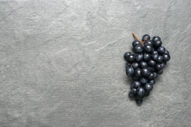 Taş yüzeyinde bir grup siyah üzüm fotokopi alanı ile düz bir zemin oluşturmuş..