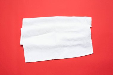 Kırmızı düz zemin üzerinde beyaz havlu uzanır.