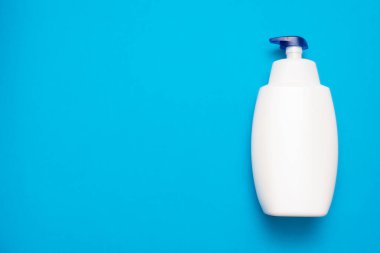 Mavi düz zemin üzerinde beyaz sıvı sabun şişesi fotokopi alanı ile yatıyordu.