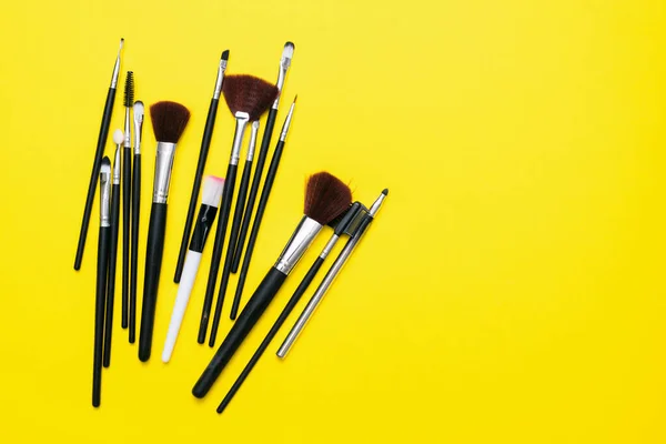 Varios Pinceles Maquillaje Negro Fondo Plano Amarillo Con Espacio Copia —  Fotos de Stock
