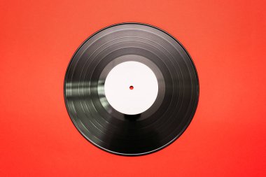 Kırmızı düz zemin üzerinde eski vinil plak.