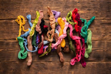 Kahverengi masa zemininde renkli nakış iplikleri.