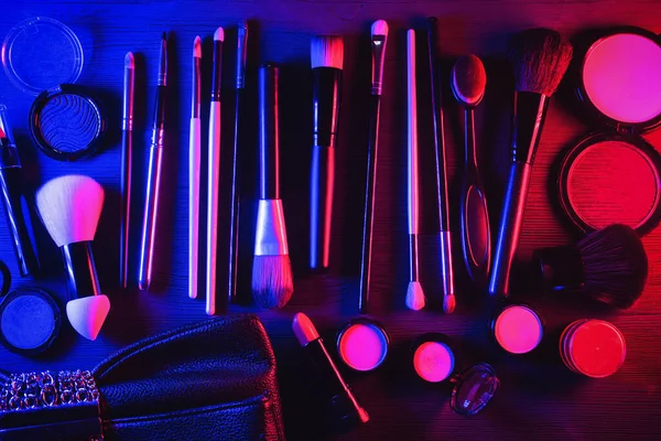 Makeup accessories concept background. Make up brushes and clutch bag on the table.