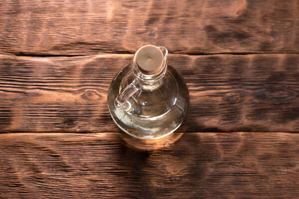 Bottle with cooking oil on the wooden kitchen table background.