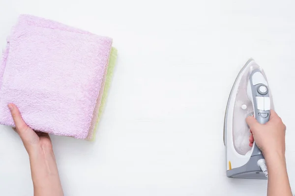 Woman with a iron and towel in hands on a white background with copy space. Ironing concept.