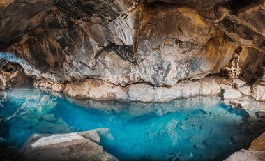 İzlanda ulusal parkında mağara Thingvellir ve mağara Tingvelir. Mavi su ve içinde büyük kayalar ve taşlar.