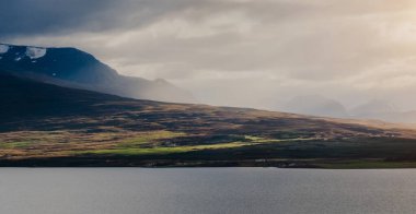 Güzel panoramik günbatımı bulutlardan gelen güneş ışığıyla dağlara bakıyor. Destansı ve inanılmaz dramatik manzara resmi.