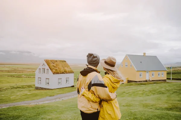 Cuplu minunat în haine galbene care caută casele de gazon din ferma icelandică Glaumbaer. Islanda destinație de călătorie . — Fotografie, imagine de stoc