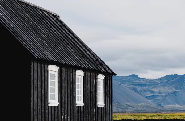 Чёрная церковь на лугу и поле в Исландии. Закрытие черных стен и белых полос окон . — стоковое фото