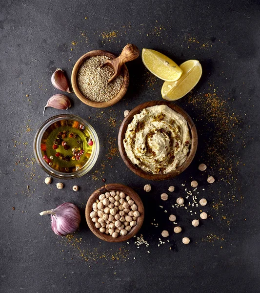 Mangkuk dengan hummus lezat dan kacang arab di latar belakang hitam — Stok Foto