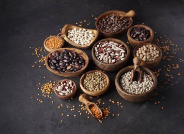 Organik Kuru fasulye ve mercimek kase siyah arka plan üzerine ürün yelpazesine. Dengeli beslenme, yemek, Vejetaryen, ham ve temiz yemek kavramı. Sağlıklı gıda.