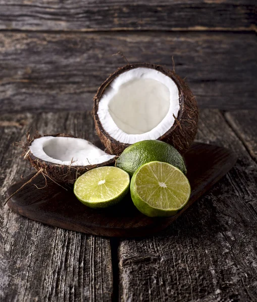 Coconut  with limes on a wooden background