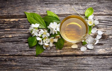 Yasemin çiçekleri ve sağlıklı çay, bitkisel ilaç. Yeşil çay ile Yasemin ahşap arka plan üzerinde