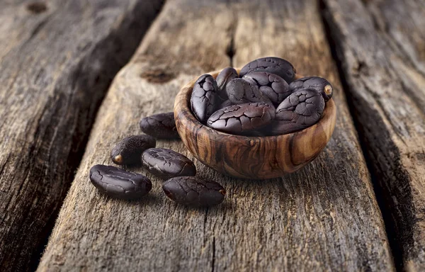 Frijoles de cacao en cuenco de madera sobre fondo de madera —  Fotos de Stock