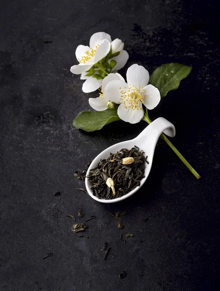 Jasmin blommor och grönt te på en svart bakgrund. Växtbaserade med — Stockfoto
