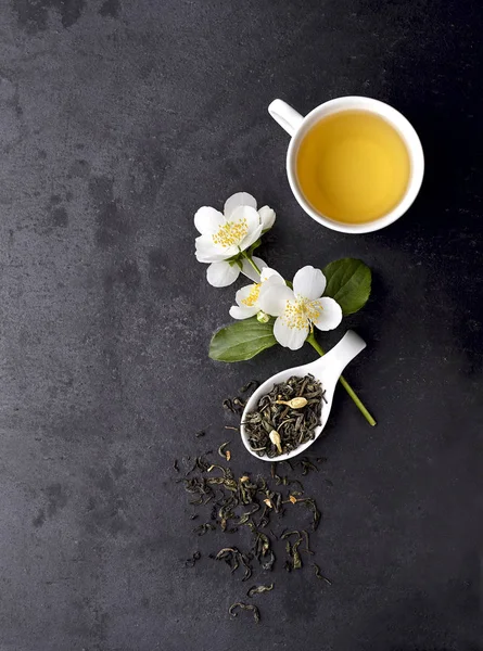 Jasmin blommor och kopp friskt te på en svart bakgrund. H — Stockfoto