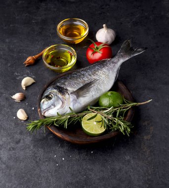 Ahşap tabakta limon, biberiye, domates ve sarımsaklı Dorado balığı..