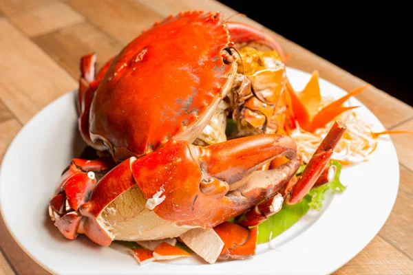 Steamed crab or Boiled crab fresh with crab\'s spawn in white dish showing the delicious crab\'s eggs inside its shell on wood table. Thai seafood.