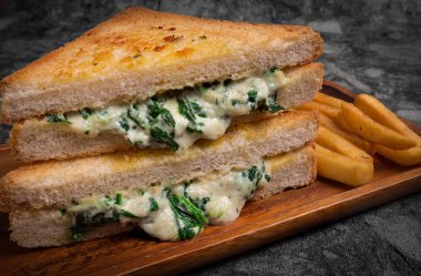 Genç ıspanaklı Çift Kişilik panini preslenmiş vejetaryen bırakır, soğan ve peynir kızartması ve ahşap plaka üzerinde sos ile servis.