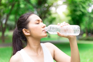 Sırasında çalışan bir kadın içme suyu. Kadın parkta koşu. Güneşli bir gün. İçme modu.
