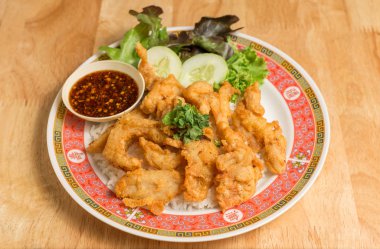 Kızarmış tavuk koyun üstüne pirinç salatalık ve sos ile.