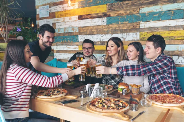 Pizza ile kutluyor ve restoran bar bira içme mutlu genç arkadaşlar, dostluk kavramı ile birlikte vaktinizi ve rustik pizzacıda gerçek eğlenmek gençlerin Şerefe