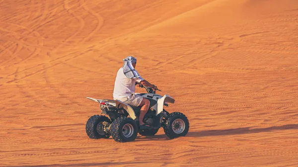 One man on Quad Bike ATV exploring desert alone with head covered by keffiyeh, Adventure concept with tourist discover earth on Quad Biking Dubai Tour, Dune bashing and Dune buggy activities