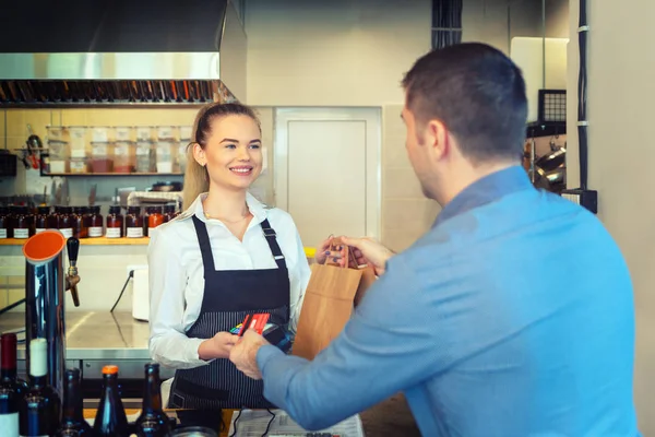 Okuyucu holded gülümseyen garson Dükkanı sayaç restoranda çalışan tarafından üzerinde kredi kartıyla ödeme paket servisi olan restoran sipariş dostum. Müşteri ödeme için kredi kartı kullanmak. Genç kasiyer nfc teknolojisi üzerinden ödeme kabul