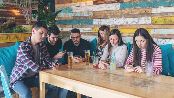 Grupo de amigos en el restaurante ignorándose unos a otros a favor de — Foto de Stock