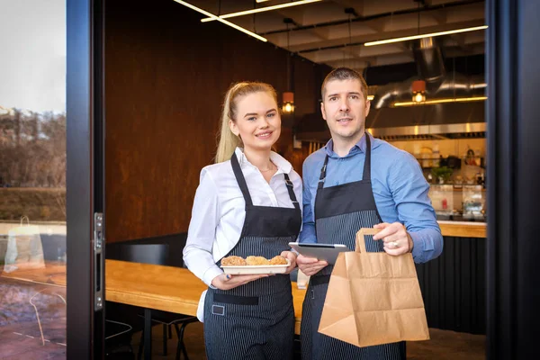 Küçük işletme sahipleri çift ayakta müşteriler, erkek ve kadın kahve dükkanı dijital teknolojiler ile üst tutmak katılıyor ve paket servisi olan restoran Siparişler teslim trendy Restoran kapı aralığında