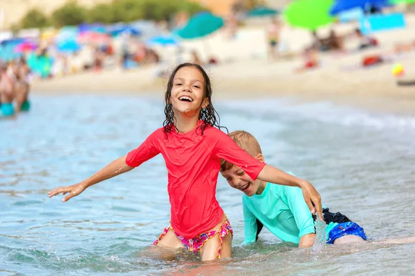 Water play with two happy children having fun at beach, Friendship concept with smiling boy and girl enjoying time together playing in water on summer vacation