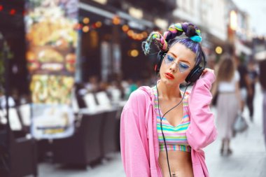 Popüler gözlüklü cool funky genç kadın kulaklık açık müzik dinlerken - güneş gözlüğü ve piercing ile hipster kız müzik vibes zevk, çılgın saçlı kız genç ile sokak moda bakmak