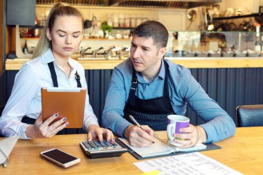 Küçük aile Restoran sahipleri finansman hesaplama faturaları ve yeni küçük işletme giderleri tartışmak-vurguladı adam ve kadın evrak birlikte kahve dükkanda gidiyor