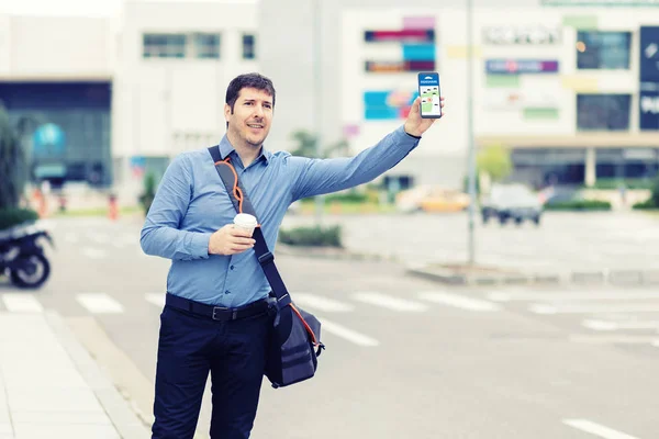 Rideshare için bekleyen cep telefonu uygulamasını kullanan genç adam - Bin yıllık iş adamı kaldırımdan gelen taksiyi arayarak - Taksi çağırmak için online haritayı kullanarak şehir merkezinde ki işten sonra erkek yolcu
